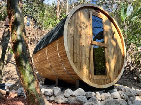 Wooden barrel sauna nestled among tropical hillside foliage at Villa Wanderlust